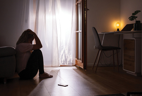 a woman sits in profile on the floor with her hands to her head