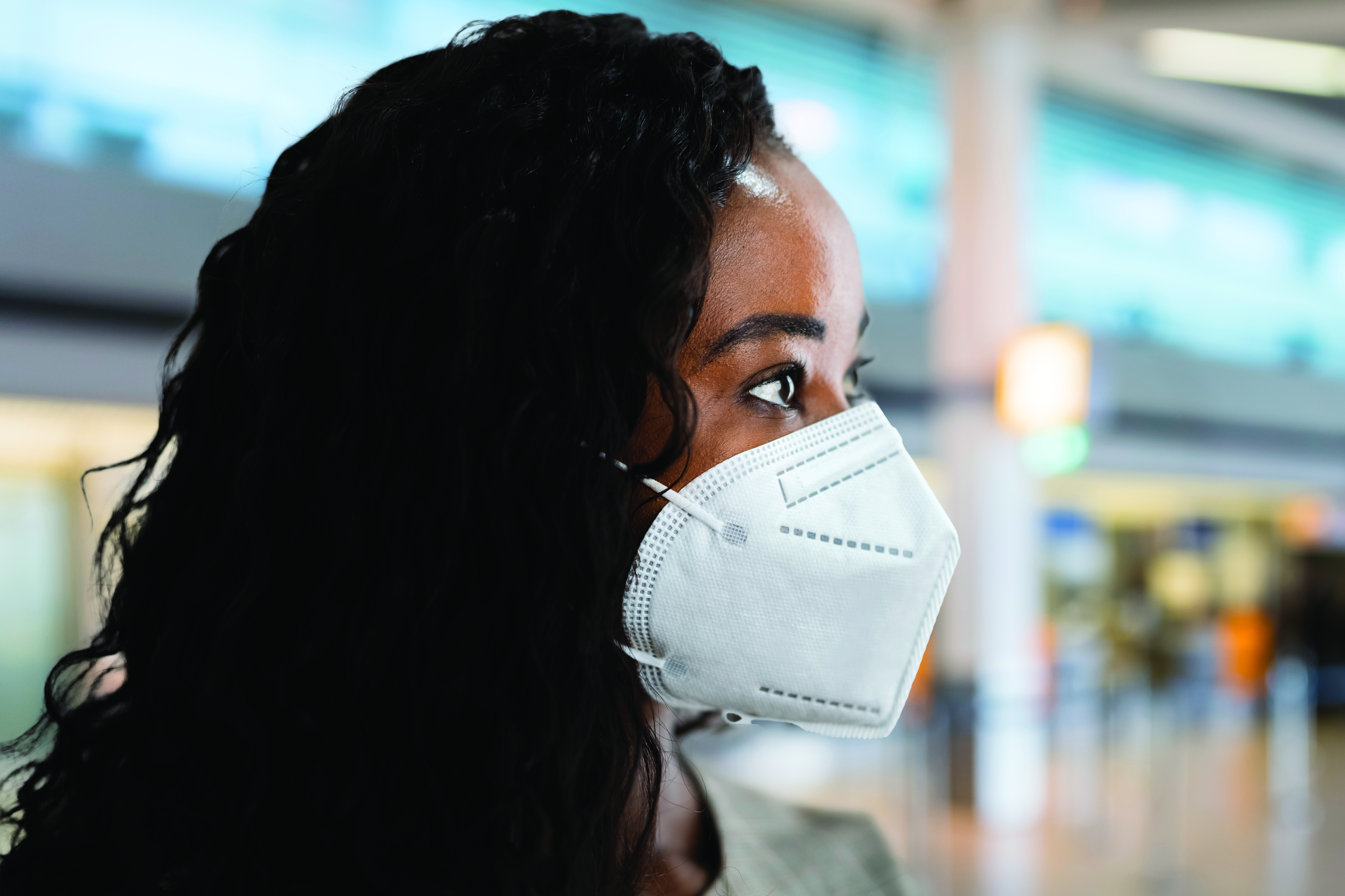 a woman's profile in a public space wearing a mask