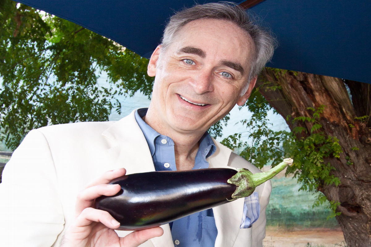 Timothy Harlan holding an eggplant at the farmers markey