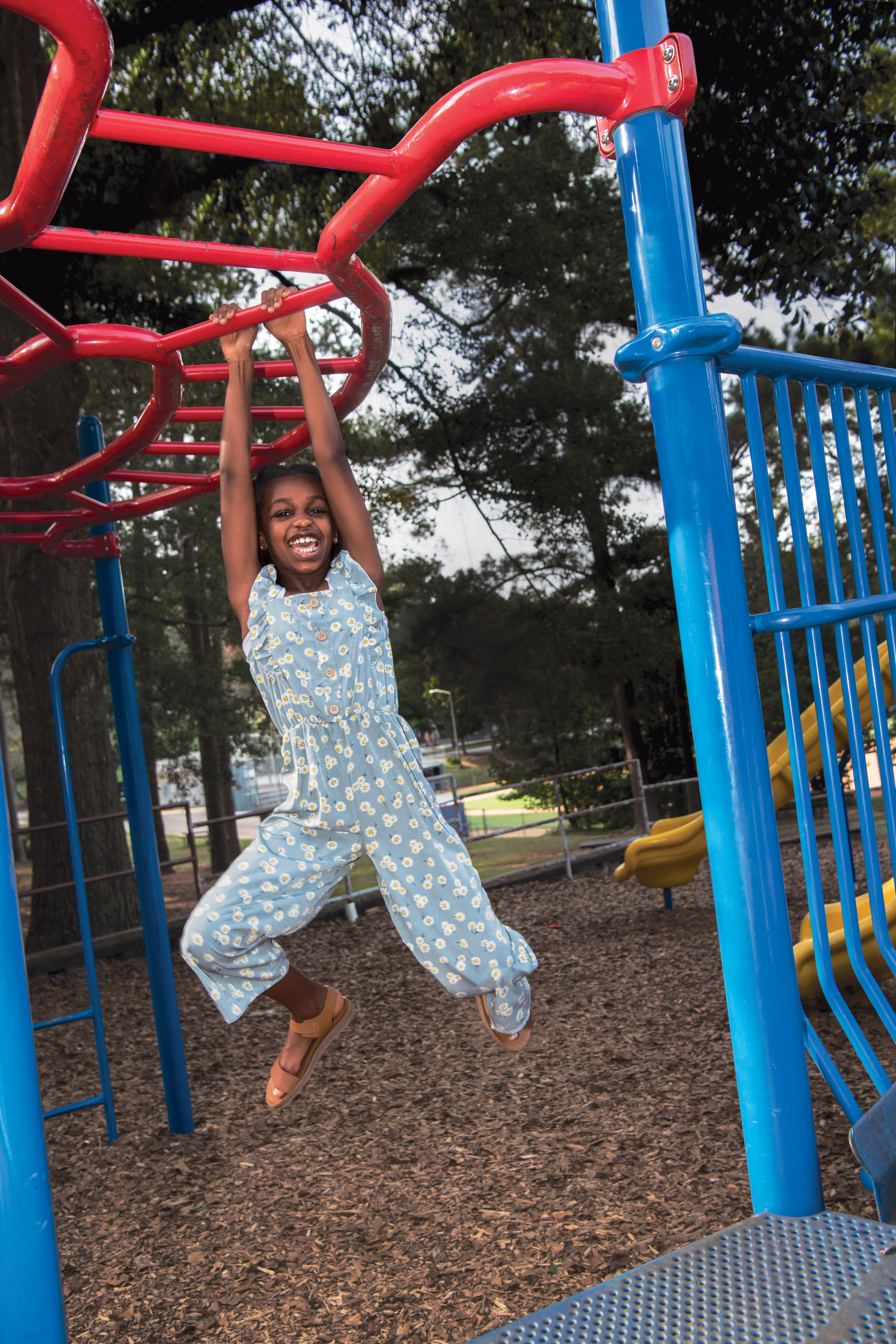 A young girl happily plays on playground equipment